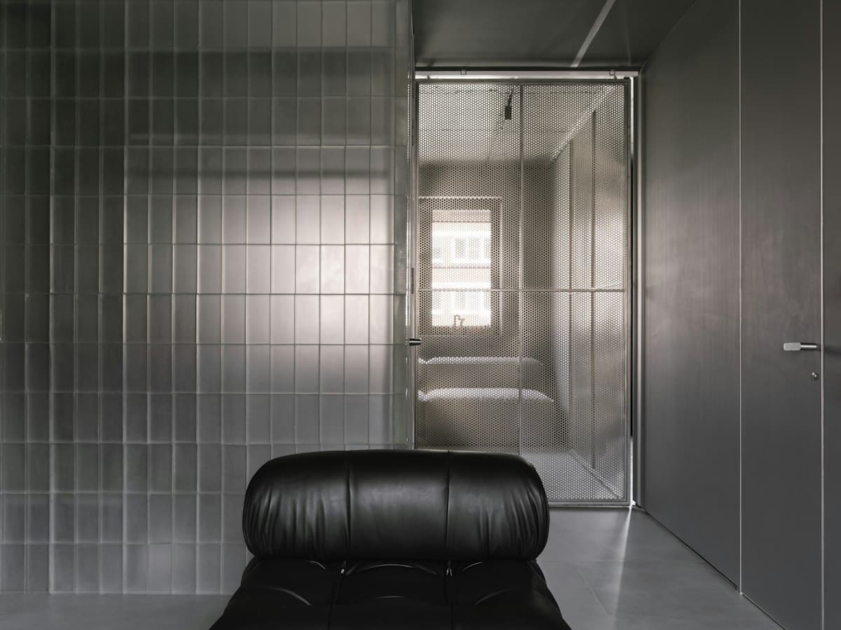 Seamless grey microcement interior with a black leather chair